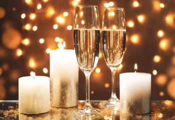 Champagne glasses and candles against blurred lights background, Champagne glasses and candles against blurred lights background, space for text
